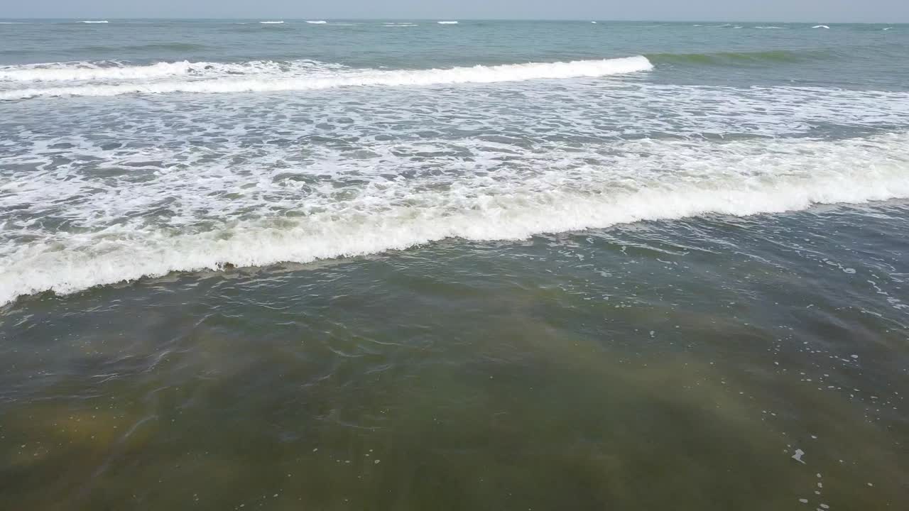 Ripresa aerea in avanti con dolly da Cape Point, Bakau, Gambia, Africa, con vista di un mare bellissimo e onde calme in una soleggiata giornata estiva.