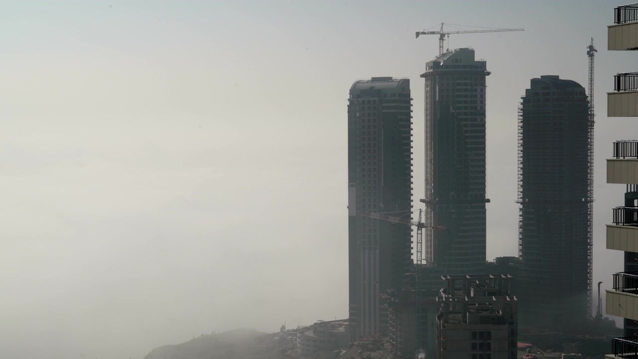 Rascacielos elevándose sobre la densa niebla matutina en un paisaje urbano.