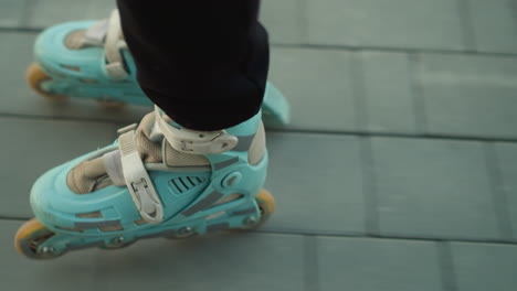 a close-up shot capturing the motion of rollerblades as they glide smoothly over a paved path in a park. the focus is on the intricate pattern of the stone bricks beneath the wheels