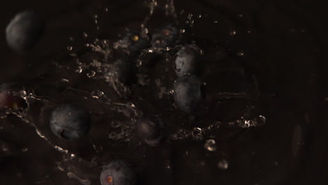 blueberries falling on wet black surface