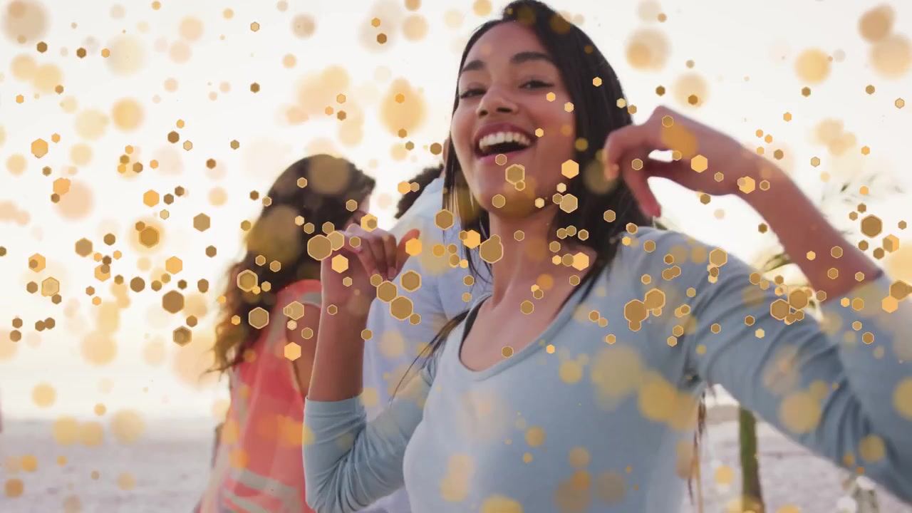 Telecamera frontale che invita a focalizzarsi su una donna che balla in spiaggia per una promozione, con bokeh dorato che fluttua sui volti.