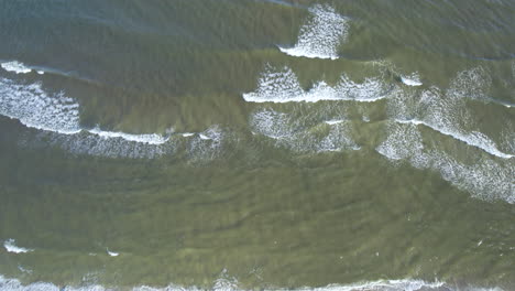 aerial top down shot of breaking waves in baltic sea during sunny day
