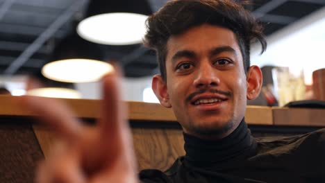 Happy-Sri-lankan-man-with-a-goatee-and-black-turtleneck-sweater-talking-and-smiling,-closeup