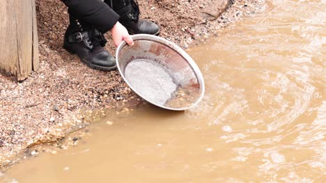 person panning for gold in muddy water