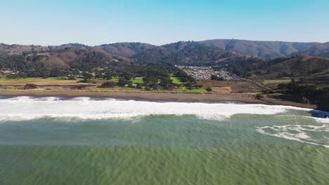 Luftaufnahme-Der-Küstenklippen-Von-Mori-Point-Beach-Mit-Türkisfarbenen-Wellen,-Die-Das-Ufer-Treffen,-Drohnenschwenk-Links