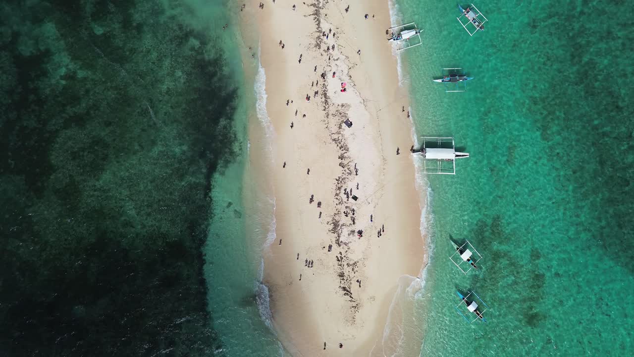 Top view shot of bare island with boats docked and people enjoying the beach