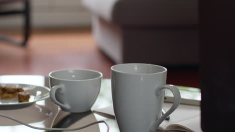 close up of hot drink in cup on table at home with snack and computer connection cables