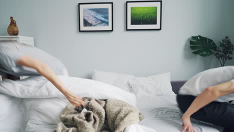 pareja teniendo una pelea de almohadas en la cama