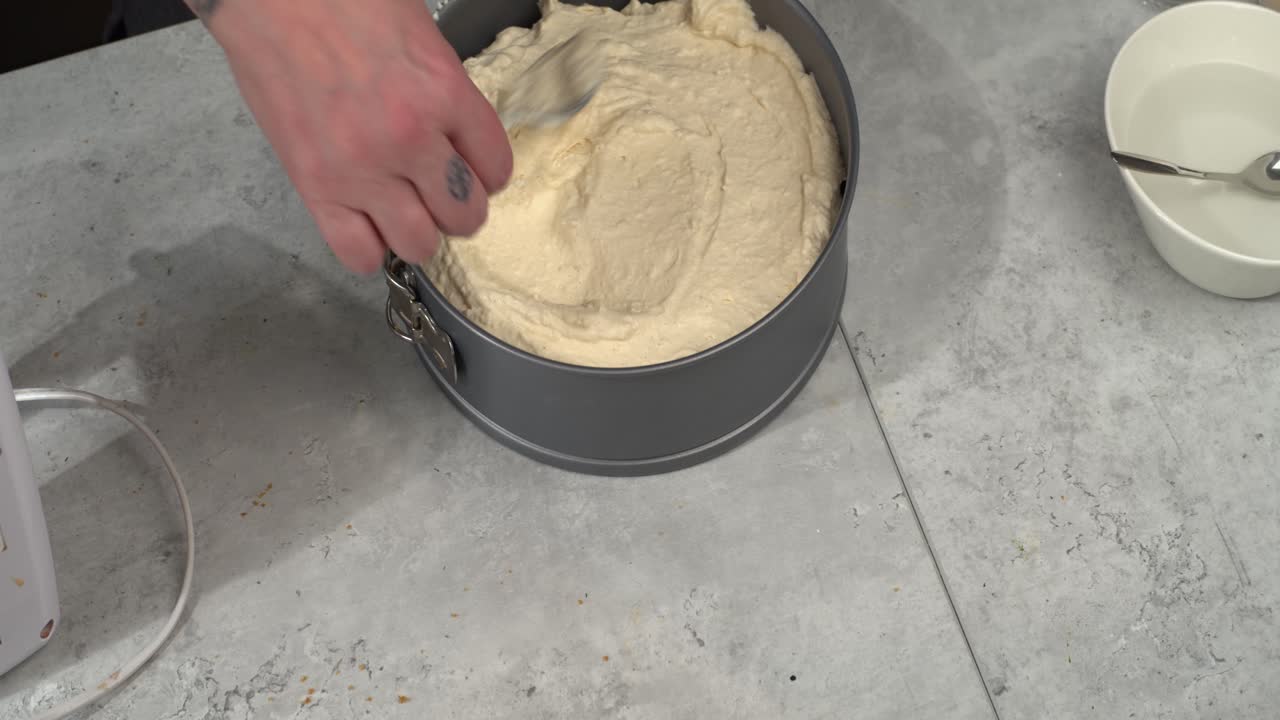 Cheesecake filling smoothed onto crumble crust in springform pan