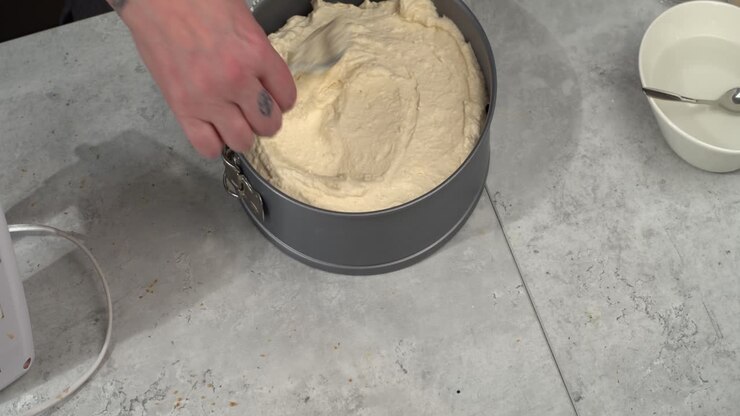 Cheesecake filling smoothed onto crumble crust in springform pan