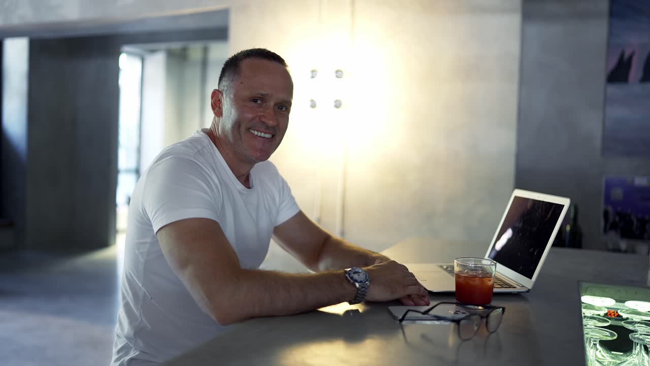 Smiling businessman working on laptop computer at home office. Male professional typing on laptop keyboard at office workplace