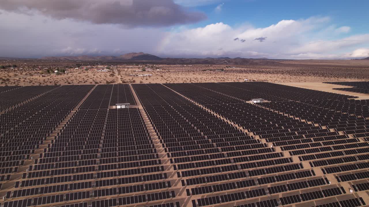 Droneoptagelser fra luften af et solcelleanlæg i Joshua Tree Nationalpark på en solskinsdag med regnbue i baggrunden, horisontal panorering bagud