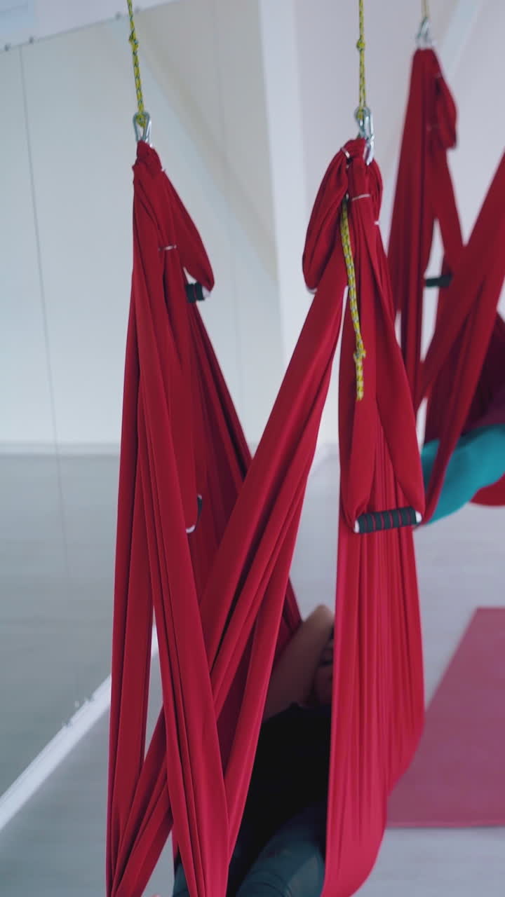 camera moves along long hammocks hanging with relaxed women tired of advanced aerial fly yoga class
