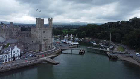 ancient caernarfon castle welsh harbour town aerial view medieval waterfront landmark push in slow right