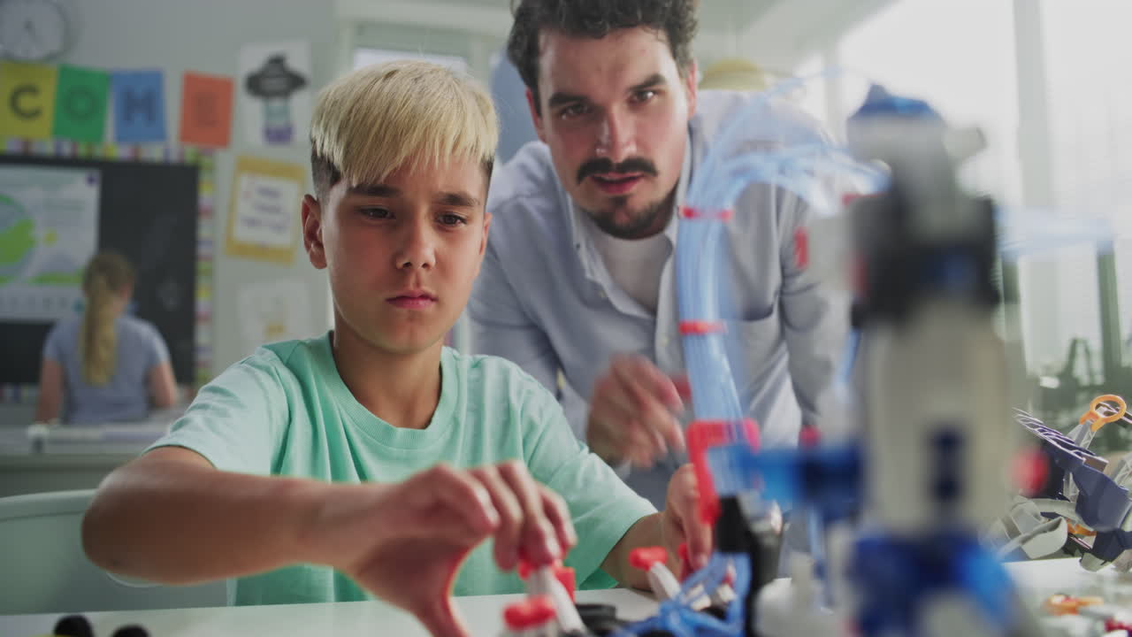 Talented Young Boy Sitting at the Desk Studying Robotic Arm Model