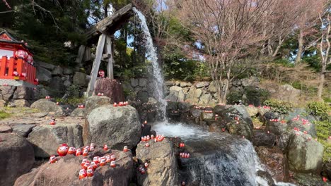 cinematic slow motion tilt up over small waterfall at katsuo-ji shrine in japan