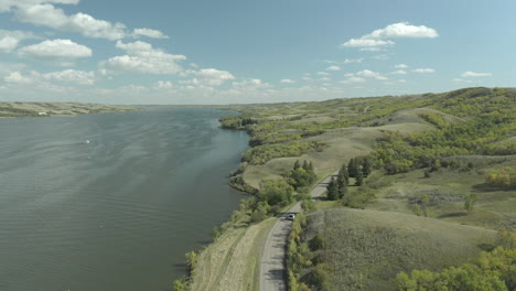 drone over traveling car on coastal road at buffalo pound provincial park, saskatchewan, canada