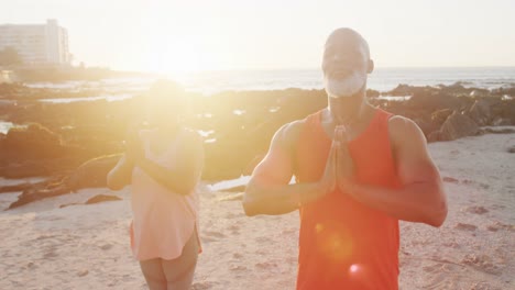 Feliz-Pareja-Afroamericana-Mayor-Haciendo-Yoga,-Meditando-En-La-Playa,-Cámara-Lenta