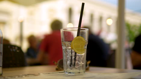 Centrarse-En-Un-Vaso-Transparente-De-Agua-Con-Gas-Con-Limón-Y-Una-Pajita-Negra