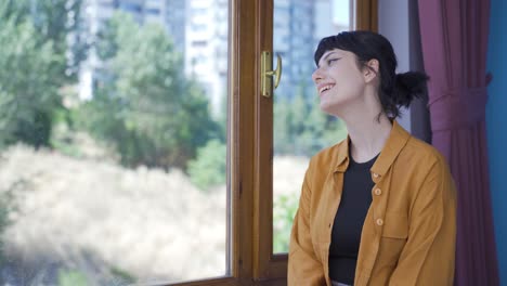 행복하고 평화로운 젊은 여성. 그녀는 창문 앞에 앉아 있습니다.