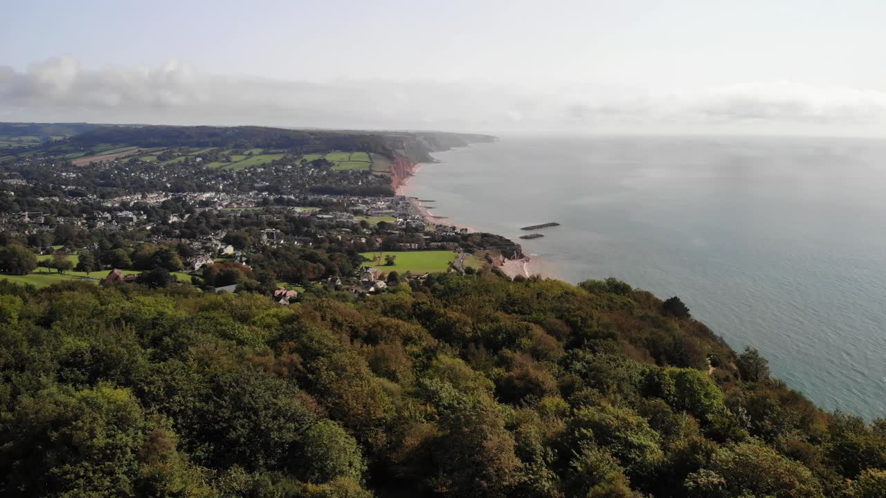 imágenes aéreas volando sobre árboles mirando hacia sidmouth y lyme bay, devon, reino unido