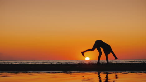 Silhouette-Eines-Kleinen-Mädchens,-Das-An-Einem-Malerischen-Ort-Am-Meer-Ein-Akrobatisches-Rad-Macht