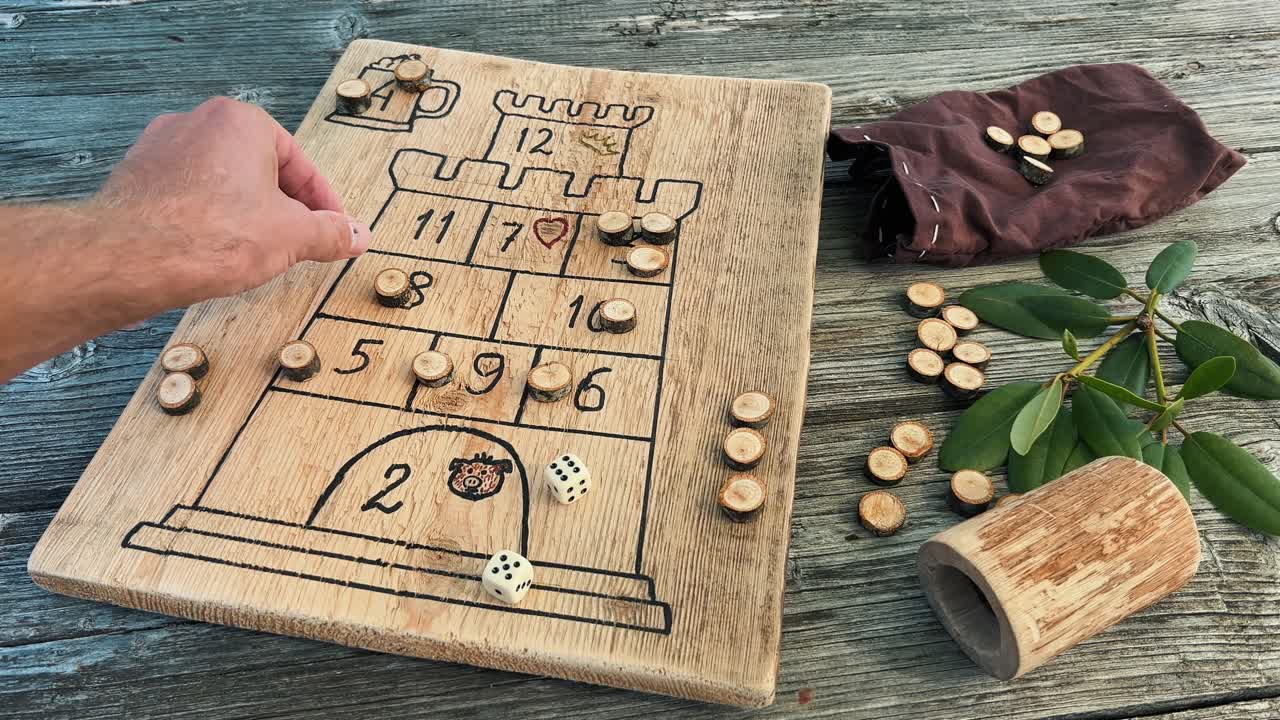 Captivating flat lay featuring a handcrafted wooden board game with a castle design, dice, wooden counters, and a small bag on a weathered wooden table