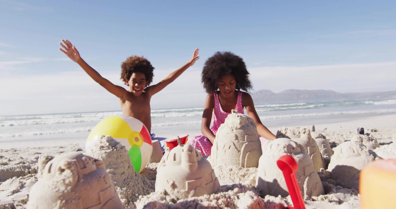 Siblings making sand forts on beach, boy raising arms sparking social badges fading while cheering