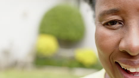 Half-face-of-happy-african-american-senior-woman-laughing-in-sunny-garden,-slow-motion