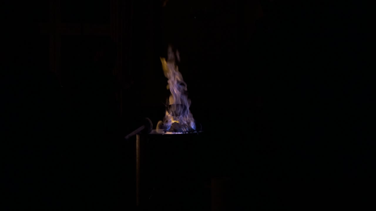Intense Blue and Yellow Flames Burning in a Metal Container at Night