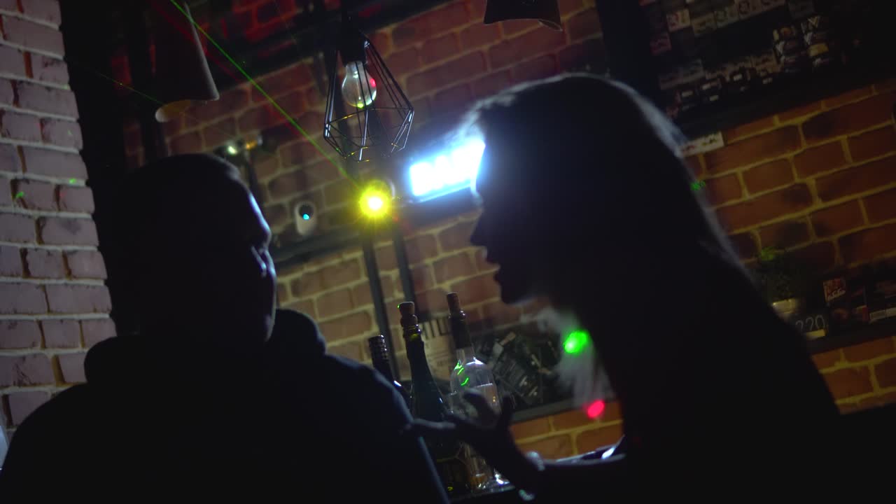 Silhuetter av mennesker som snakker på en bar om natten
