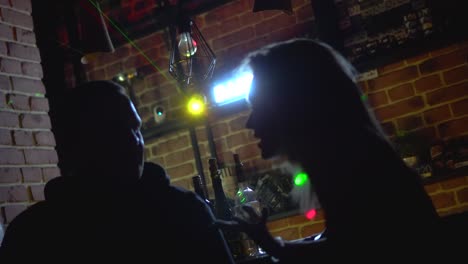 silhouettes of people talking at a bar at night