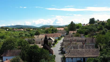 Drone-flies-over-the-historical-streets-of-Holloko,-Hungary-in-the-afternoon