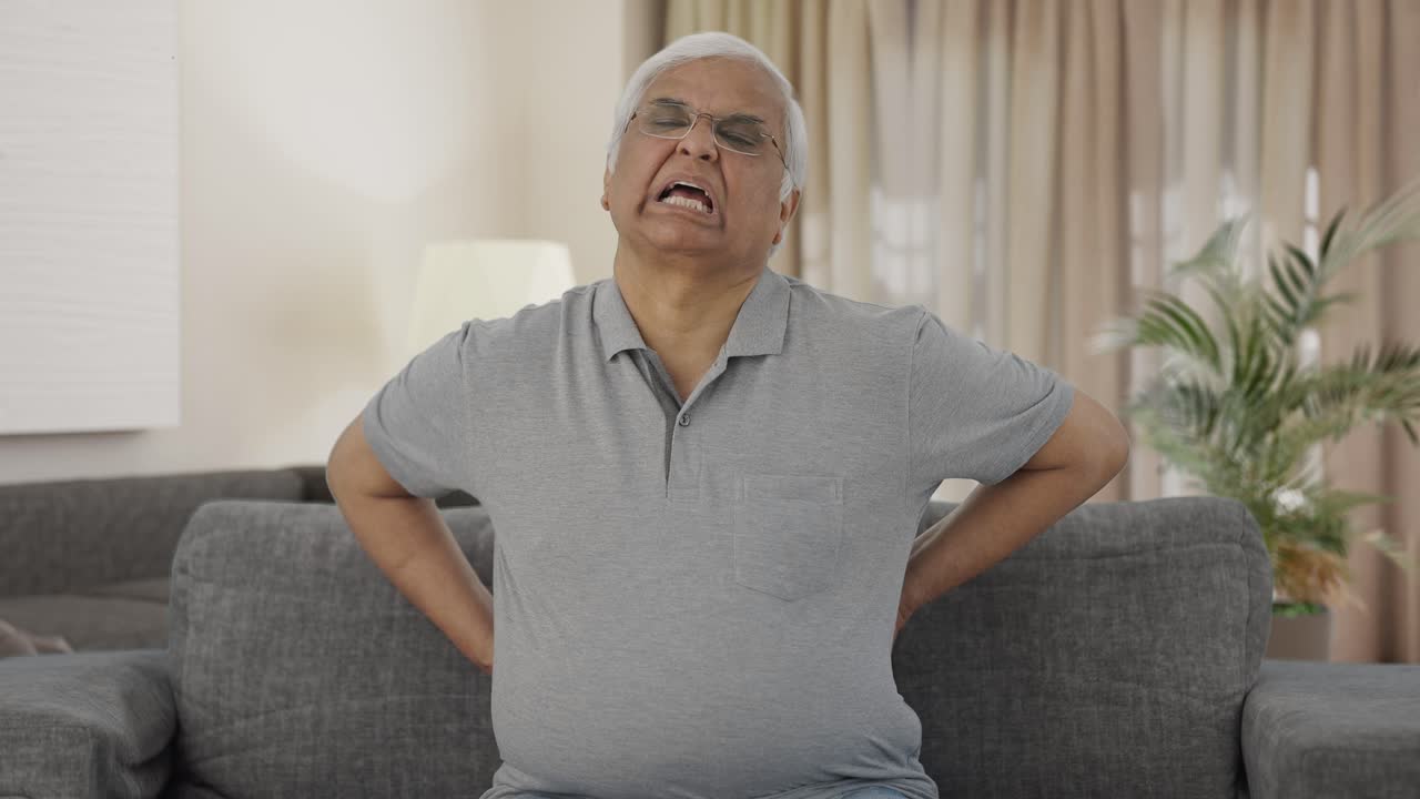 Sick Indian old man suffering from back pain