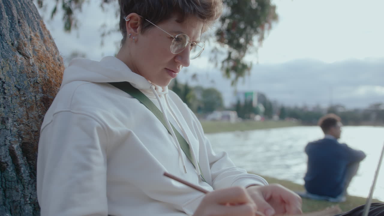 Female Student Using Laptop and Making Notes in the Park