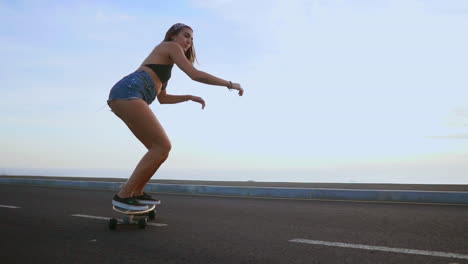 disfrutando de la serena puesta de sol, una mujer patinadora monta a lo largo de una carretera en cámara lenta, con montañas y un cielo impresionante como telón de fondo.
