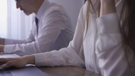 brunette employee checking the mail on the computer and having a conversation on the phone, while her employee talks and works