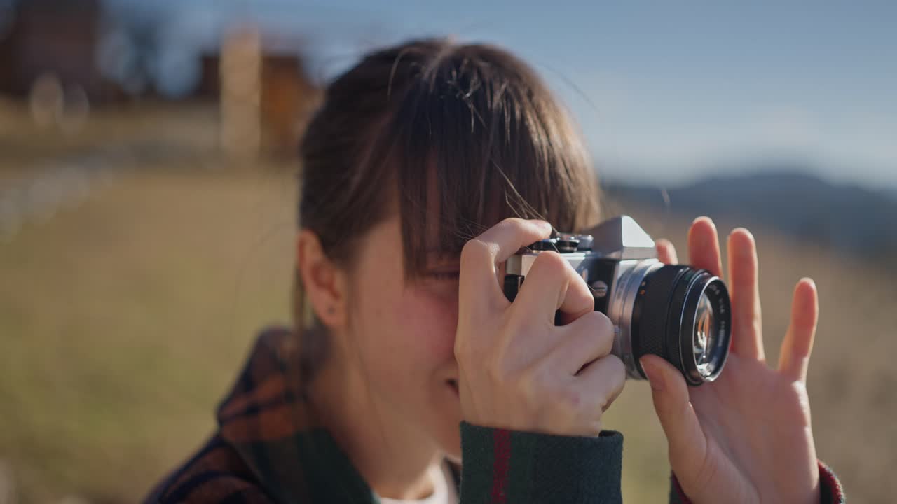 Woman taking photos with a film camera outdoors