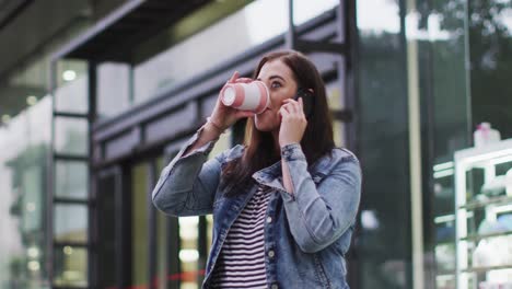 young caucasian woman drinking coffee while being on phone