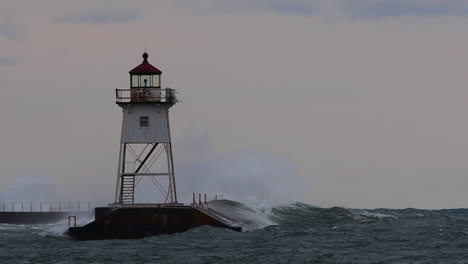 waves crashing a lighthouse in grand marais, minnesota during storm in slow motion