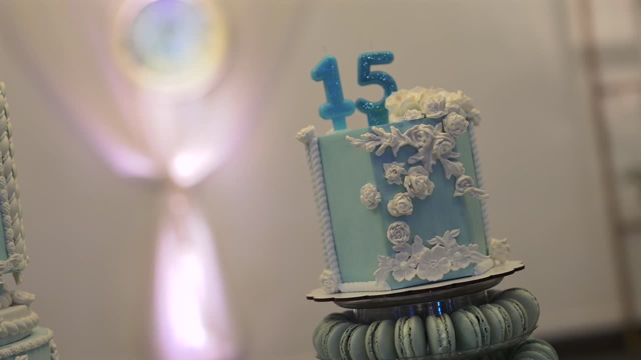 Smooth right moving footage of light blue, flower decorated Quinceañera birthday cake against a clean white background