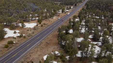 Car-Driving-On-Country-Road-Between-Trees-And-Fields-In-Kaibab-National-Forest-In-Arizona---aerial-shot