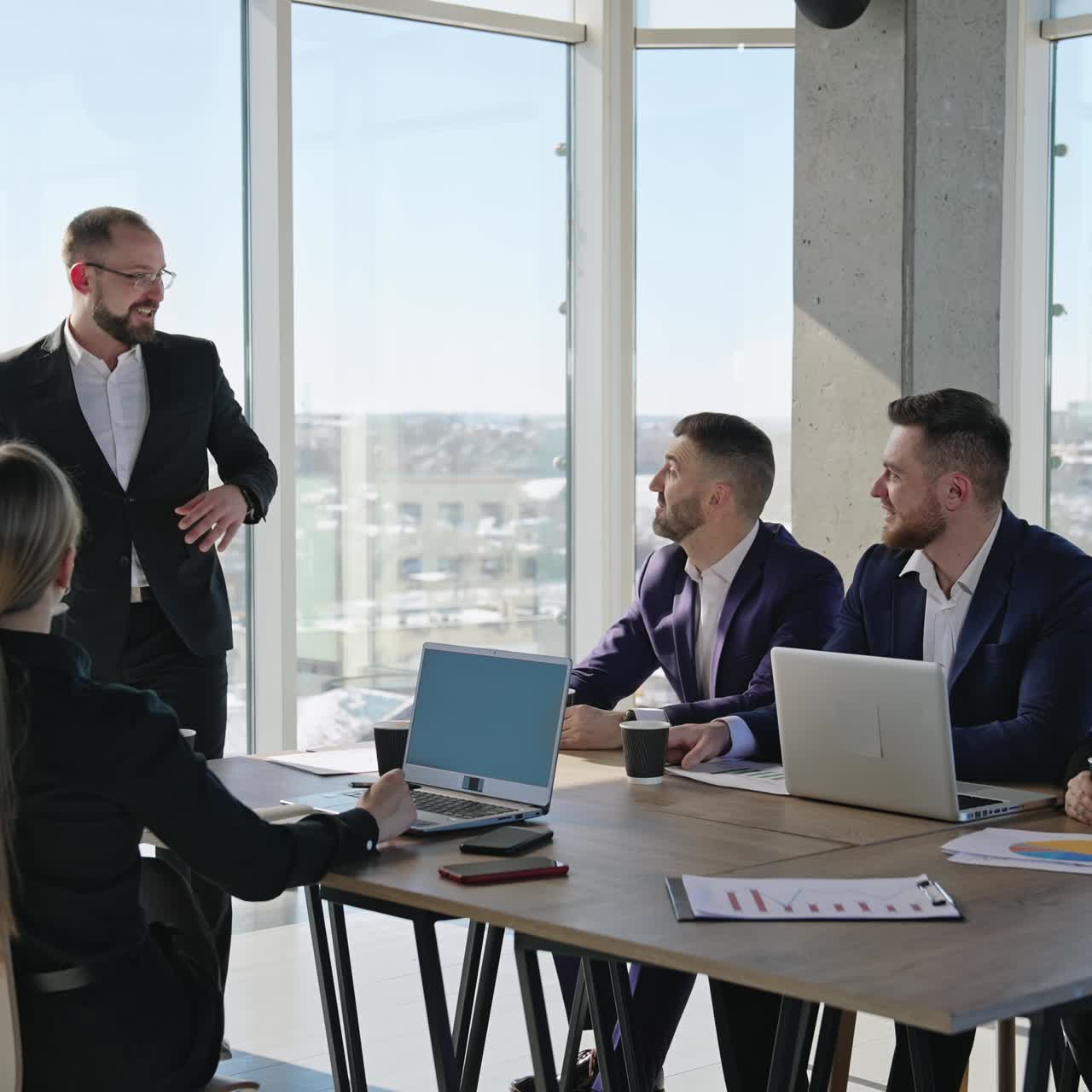 Colleagues are having meeting in sunlit office. Friendly communication and building strategies in the office team. City at the backdrop