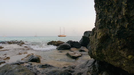 rocks revealed floating boats on the splashing sea of fuerteventura in spain’s canary islands