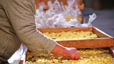 ältere-Italienische-Frauen,-Die-Handgemachte-Traditionelle-Orecchiette-Nudeln-Auf-Den-Straßenmärkten-Von-Bari,-Italien,-Apulien,-Herstellen-Und-Verkaufen,-Die-Trockengestelle-Bewegen-Und-Einstellen,-Statische-Aufnahme,-Keine-Gesichter,-Hell,-Sonnig