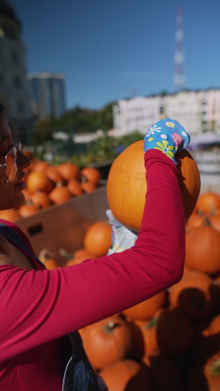 mujer recogiendo una calabaza en un mercado de otoño