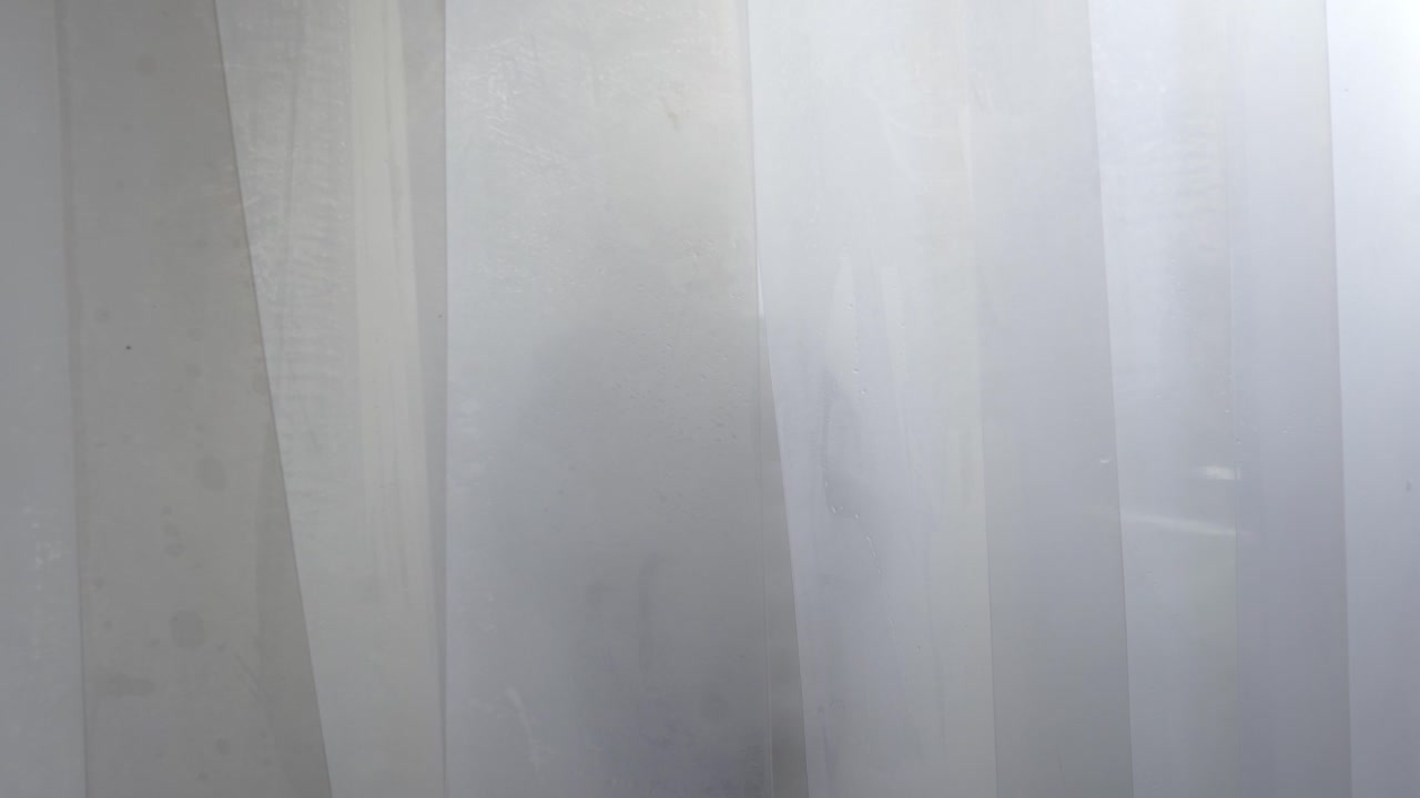 chica mirando a través de una cortina de la ventana