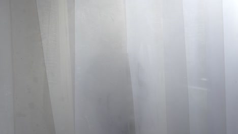 chica mirando a través de una cortina de la ventana