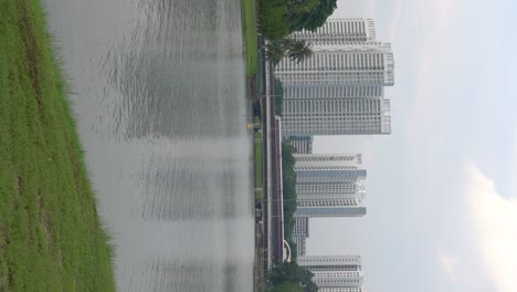 Vertical-video---someone-kayaking-at-the-distance-,-train-passing-by,-Singapore