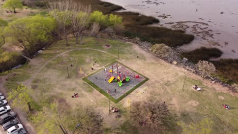 toma de órbita aérea de niños jugando en el parque cerca de la orilla del río en buenos aires a la luz del sol